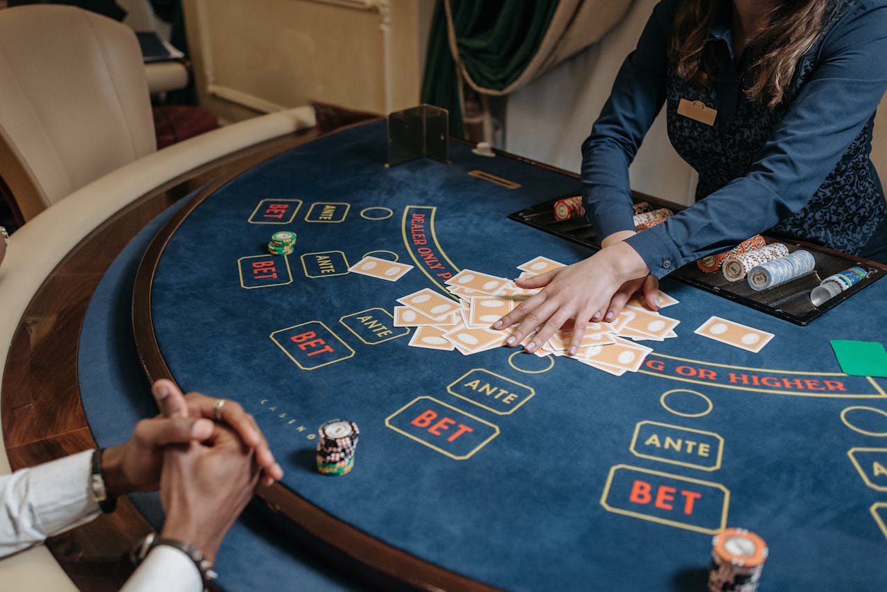 Dubibet Casino Login | Direct Access to Slots & Live Gambling. Close-up of a casino dealer shuffling cards on a gambling table with chips and bet labels.