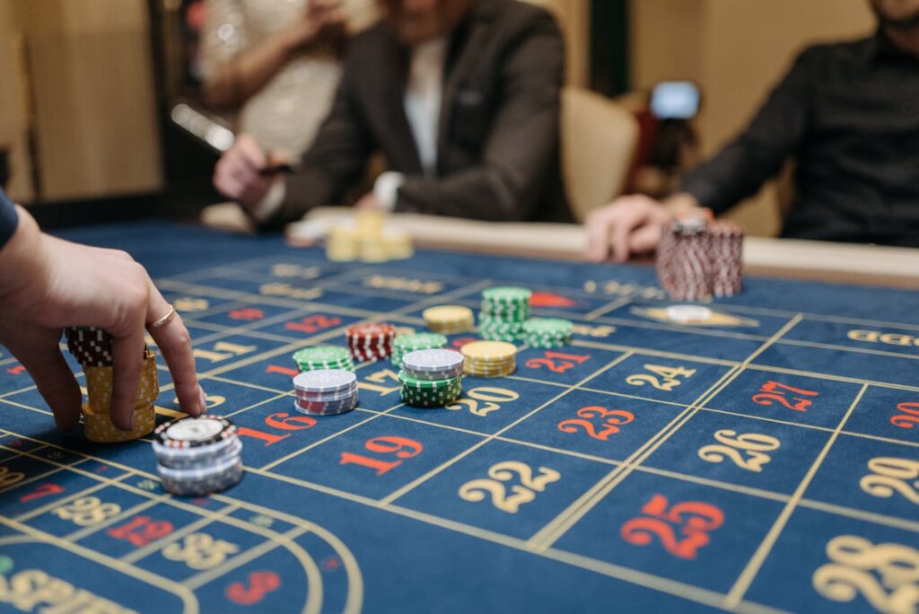 Dubibet Online Casino Entry | Official Login & Gambling Access. Hands placing betting chips on a roulette table in an upscale casino setting.